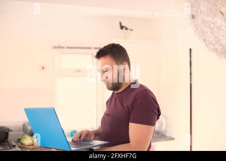 Uomo che lavora da casa al laptop Foto Stock