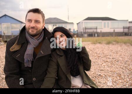 Felice coppia in cappotti invernali sulla spiaggia Foto Stock