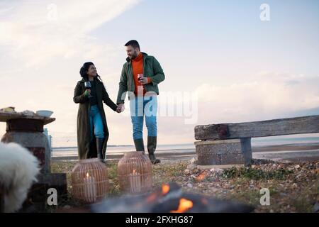 Coppia con vino che tiene le mani sulla spiaggia Foto Stock