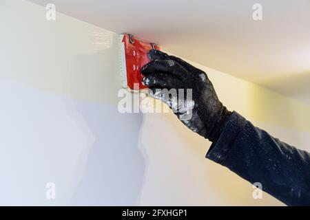 Utensile da costruzione per l'utente di un'azienda che lavora in un edger di vernice ad angolo pennellare le mani del pittore nel quadro della parete Foto Stock