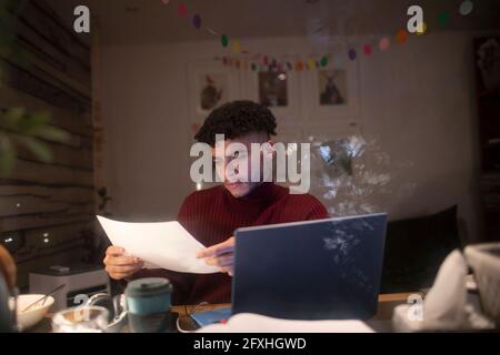 Giovane uomo concentrato con lavoro di documenti tardi in ufficio domestico Foto Stock