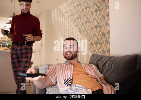 Coppia maschile gay con vino guardando la TV a casa Foto Stock