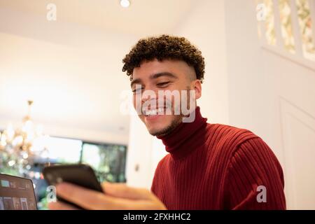 Felice giovane uomo utilizzando smart phone Foto Stock