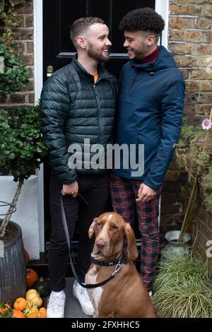 Felice coppia gay maschio con cane sul piano cottura anteriore Foto Stock