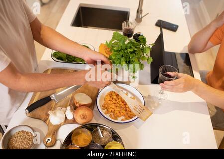 Uomo che cucina con verdure fresche in cucina Foto Stock