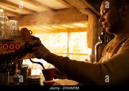 Barista maschile che prepara il cappuccino alla macchina per caffè espresso Foto Stock