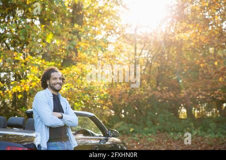 Felice uomo a convertibile nel soleggiato parco autunnale Foto Stock