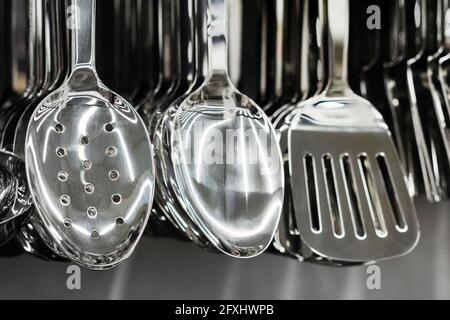 Foto del set di utensili da cucina in acciaio inox appeso al rack del negozio. Foto Stock