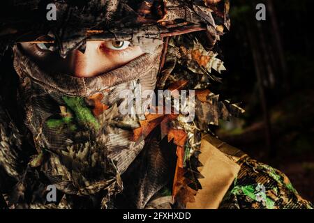Foto di un volto di cacciatore maschile a panama cappello e guillie foresta mimetizzato. Foto Stock