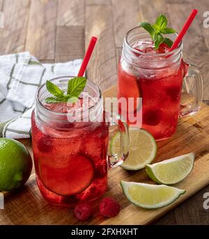 Due bicchieri di succo di mirtillo con lamponi e lime un tavolo rustico in legno Foto Stock