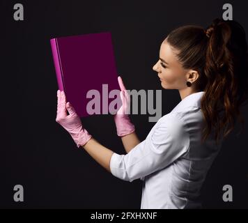 Donna medico ginecologo riproduzioni in guanti rosa in lattice e uniforme in piedi e tenendo in mano l'album viola Foto Stock