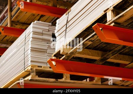 Foto di pannelli di legno compensato impilati in scaffali per magazzini di forniture edili. Foto Stock