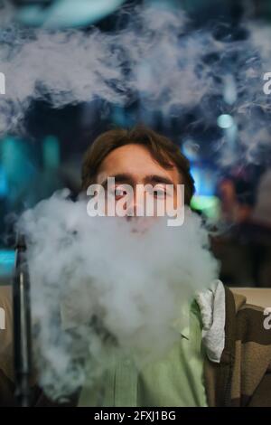 Ritratto di un giovane nel fumo. Uomo al ristorante fumo hookah. Persona sul divano nel caffè. Rilassati al bar shisha. Foto Stock