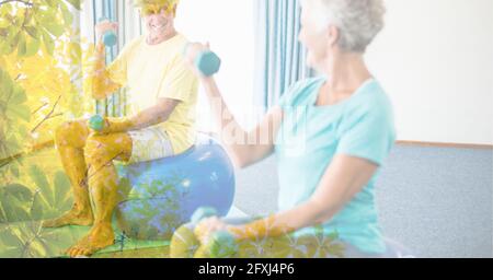 Composizione di uomo anziano e donna che solleva manubri in forma fisica classe con sovrapposizione ad albero Foto Stock