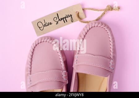 Belle scarpe da donna rosa con Onlin Shopping tag su sfondo rosa. Concetti aziendali. Foto Stock