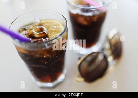 Due bicchieri con ghiaccio di cola e limone sono sul tavolo Foto Stock