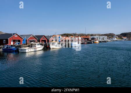 17 aprile 2021 - Hamburgsund, Svezia: Un pittoresco villaggio di pescatori sulla costa occidentale svedese. Tradizionali capanne di mare rosso e un cielo blu sullo sfondo Foto Stock