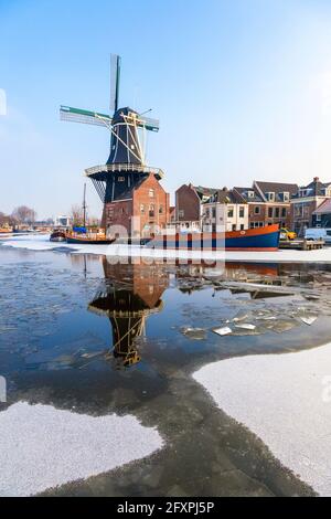 Windmill De Adriaan riflesso nel canale del fiume ghiacciato Spaarne, Haarlem, quartiere di Amsterdam, Olanda del Nord, Paesi Bassi, Europa Foto Stock