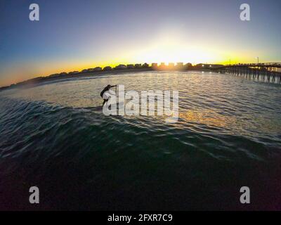 Alzati in piedi sul paddle boarder che cattura un'onda al tramonto, Nags Head, North Carolina, Stati Uniti d'America, Nord America Foto Stock