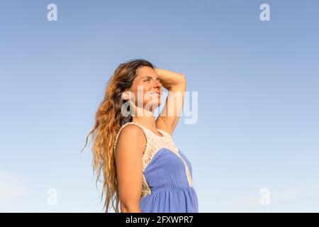 Ritratto di sorridente bella giovane femmina godendo di una giornata di sole con cielo blu. Foto Stock