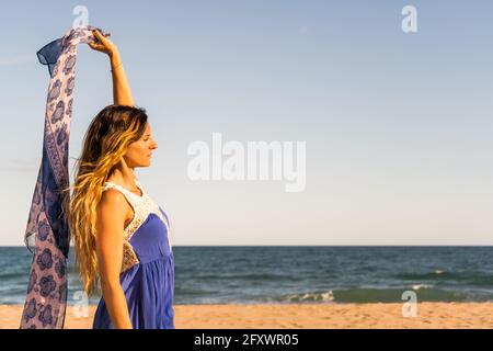 Bella giovane donna che tiene asciugamano sulla spiaggia a Sunset.Creative sfondo artistico estivo con spazio copia . Foto Stock