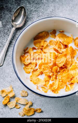 Primo piano di cereali di fiocchi di mais in ciotola su sfondo piano Foto Stock