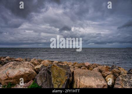 Un cielo bello e suggestivo sull'oceano. Pietre in un interruttore di onda in primo piano. Foto di Malmo, Svezia Foto Stock