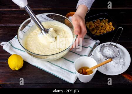 Lavorare con un frullatore in cucina. Battere l'impasto. Cugli la pasta. Frullatore nelle mani di una casalinga. La ragazza sta mescolando l'impasto con un Foto Stock