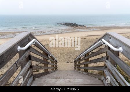 Scala in legno per una spiaggia deserta in una mattina d'autunno nebbiosa. Concetto di solitudine Foto Stock