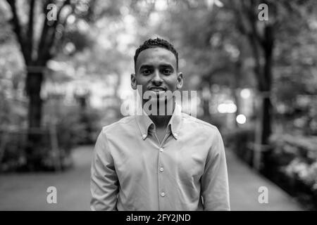 Ritratto in bianco e nero di bel giovane uomo d'affari africano nero all'aperto in città Foto Stock
