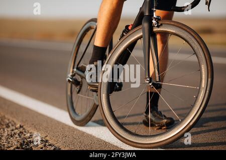 Primo piano della bici nera con il ciclista maschile seduto sopra esso Foto Stock