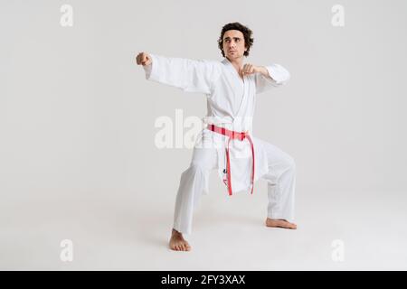 Uomo Karate che si esercita isolato su sfondo bianco Foto Stock