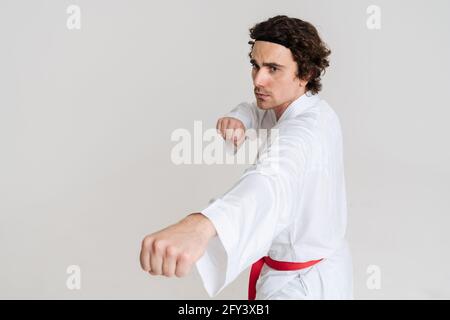 Uomo Karate che si esercita isolato su sfondo bianco Foto Stock