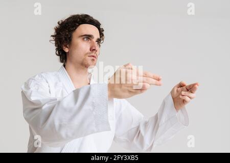 Uomo Karate che si esercita isolato su sfondo bianco Foto Stock