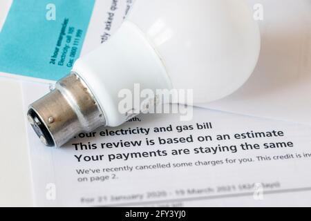 Immagine concettuale di una lampadina elettrica a baionetta su un stima della bolletta combinata di gas ed elettricità Foto Stock