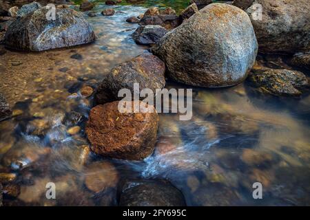 Acqua che scorre attraverso pietre e giù piccoli gradini di roccia scena naturale. Foto Stock