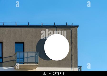 Cartello bianco rotondo mock up strada su parete grigia in cima all'edificio Foto Stock