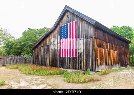 Castroville, Texas, Stati Uniti. 12 aprile 2021. Grande bandiera americana su un fienile nella regione collinare del Texas. Foto Stock