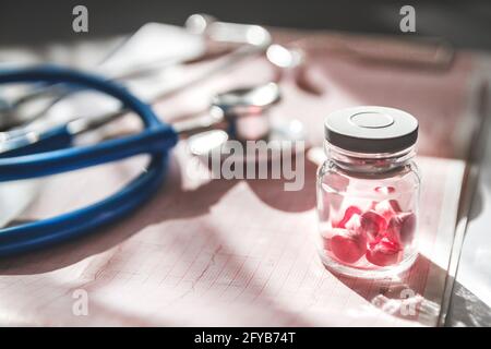 Primo piano della scheda medica di un paziente, uno stetoscopio e pillole Foto Stock