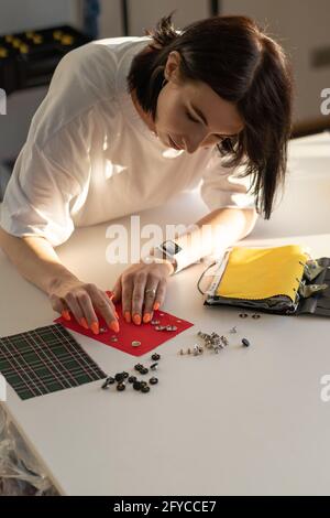 Il fashion designer sceglie accessori, bottoni e spille per la nuova collezione in laboratorio Foto Stock