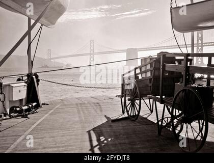 CARRI A CARRELLO A SPINTA CON SILHOUETTE ANNI '30 SUL PONTE DEL TRAGHETTO VISTA DI OAKLAND BAY BRIDGE DAL TRAGHETTO SAN FRANCISCO CA USA - Q37285 CPC001 HARS COSTA OCCIDENTALE TRAGHETTO CONCETTUALE OAKLAND I TRAGHETTI PER IL PONTE OAKLAND BAY SI ESTENDONO SU PONTI BIANCHI E NERI I PENDOLARI SI UNISCONO ALLA VECCHIA MODA Foto Stock