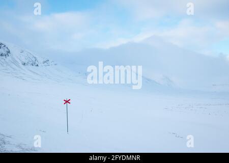 Lasciando le cabine Alesjaure all'alba mentre racchette da neve Kungsleden Trail, Lapponia svedese, aprile 2021. Le croci rosse segnano il sentiero. Foto Stock