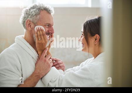 Coppia sposata gioiosa amorevole in accappatoio peluche si divertono dentro camera interna Foto Stock