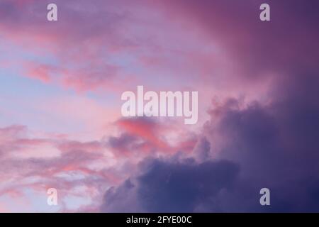 Colori tenui e vibranti nel cielo del tramonto con spettacolari nuvole di cumuli come se su fuoco con cielo blu e acceso toni magenta e rosso Foto Stock