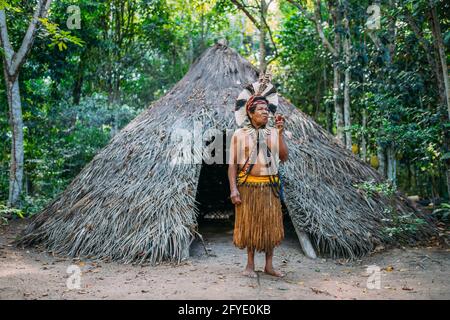 Sciaman della tribù Pataxó, indossando un headdress di piuma e fumando un tubo. Indiano brasiliano guardando la destra Foto Stock