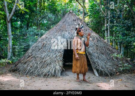 Sciaman della tribù Pataxó, indossando un headdress di piuma e fumando un tubo. Indiano brasiliano guardando la destra Foto Stock