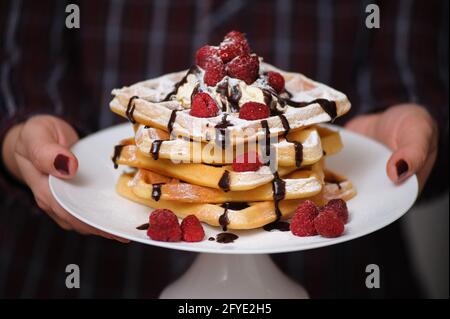 Mani che tengono cialde con lamponi Foto Stock