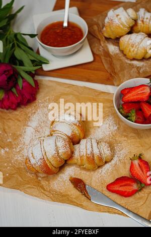 Shot verticale di croissant appena sfornati con fragole e marmellata Foto Stock