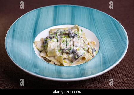 pasta con formaggio e funghi in un piatto blu Foto Stock