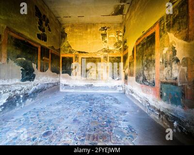 Grande triclinio (sala da pranzo) decorato nel quarto stile con semplici pannelli neri incorniciati in rosso separati da motivi architettonici tutti sopra un ampio fregio nero inferiore - Casa del Cervo (Casa dei Cervi) - rovine di Ercolano, Italia Foto Stock